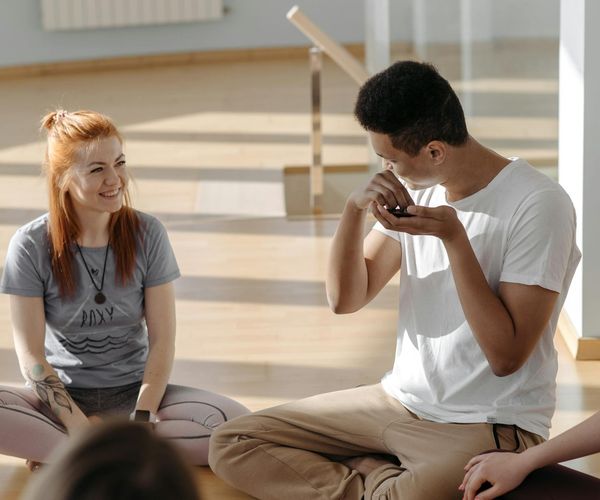 Diverse group of people smiling and relaxing in a yoga studio.