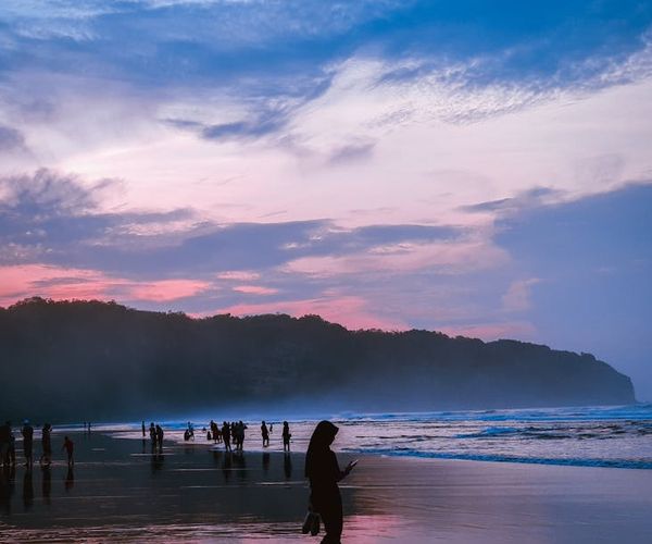 Silhouette of a person meditating during sunrise with vibrant colors.